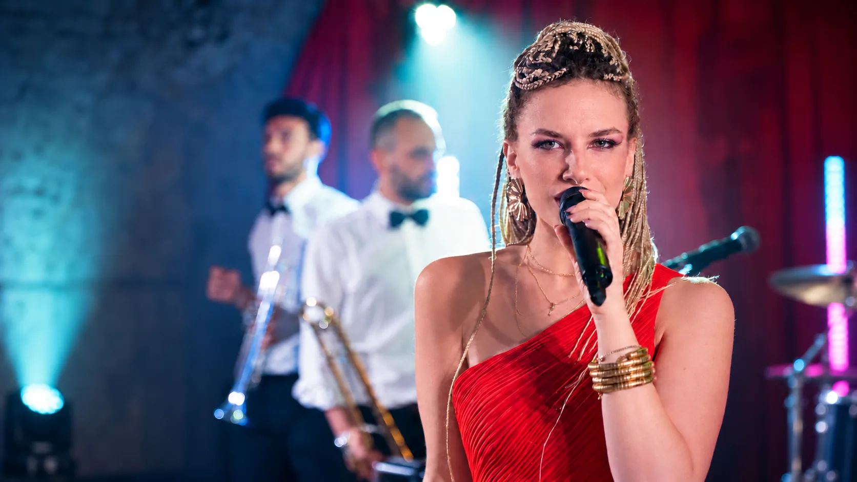 The Gloves singer in a red dress performing with brass musicians and stage lighting
