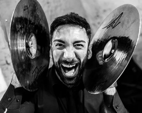 Black-and-white portrait of The Gloves drummer between two cymbals