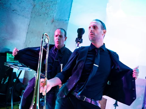 The Gloves trombonist opening his jacket beside another band member