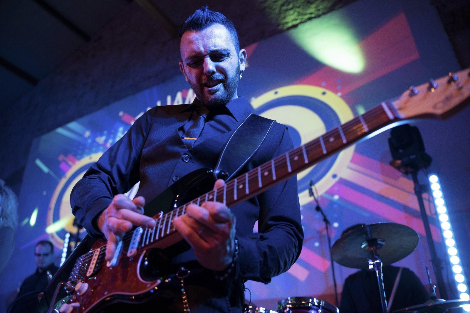 Chitarrista di una wedding band durante un assolo dal vivo sul palco a una festa di matrimonio in Italia